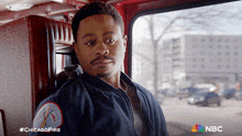 a man in a blue jacket is sitting in the back of a fire truck with the hashtag #chicagofire