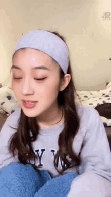 a woman wearing a headband and a sweater that says ny