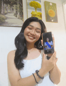 a woman is holding up a cell phone with a picture of a woman on it