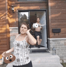 a woman holds a fake poop in front of a house with the number 790 on the door