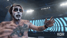 a wrestler with a tattoo on his chest is standing in front of a screen that says roh