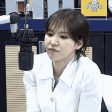 a woman in a white shirt is sitting in front of a microphone in a radio station .