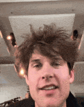 a close up of a man 's face with a messy hairdo