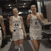 two female lynx basketball players wearing white jerseys