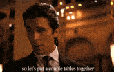 a man in a suit and tie is saying so let 's put a couple tables together