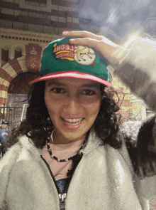 a woman wearing a green and red hat that says ' alonso ' on it