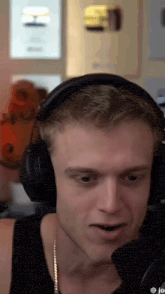 a man wearing headphones and a gold chain is talking into a microphone