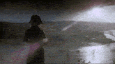 a man in a black hat stands in front of a river