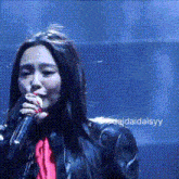 a woman singing into a microphone with the name daidaisyy written on the bottom