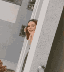 a woman is peeking out from behind a wall
