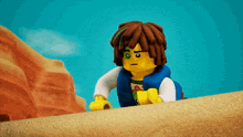 a lego figure with a green eye is standing on a sandy hill