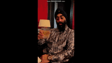 a man in a turban is holding a glass of alcohol