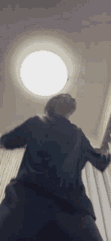 a man in a suit is standing in front of a light and looking up at it .