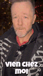 a man with a beard is wearing a black jacket that says " vien chez moi " on it