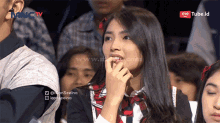 a woman sitting in front of a mnctv screen looking at something