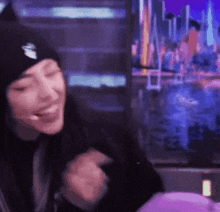 a woman wearing a beanie is sitting in front of a purple wall .