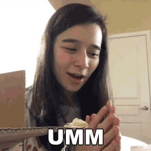 a woman is holding a piece of cake with the word umm written on her face