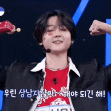 a young man is flexing his muscles while wearing a red shirt and a microphone .
