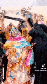 a woman in a colorful dress is dancing with a crowd of people .