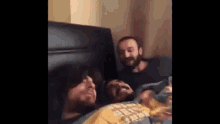 three men are laying in a bed with their heads on the headboard .