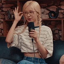 a woman wearing glasses and a crop top with the word rose on it is holding a microphone