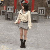 a girl standing in front of a brick wall with a shield that says t.