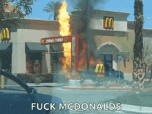 a mcdonald 's drive-thru is on fire and a car is parked in front of it