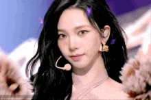a woman with long black hair is wearing a microphone and earrings