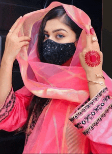 a woman wearing a pink dress and a black mask