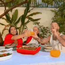 a group of people are sitting at a table with food and drinks .