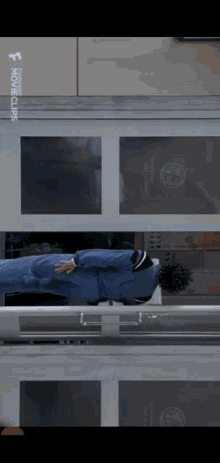 a man is laying on a bed in front of a window that says ' movieclips ' on it