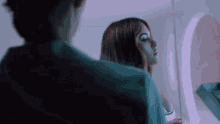 a woman is looking at her reflection in the mirror .