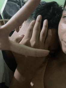 a woman covers a man 's face with her hand