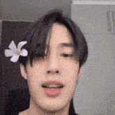 a close up of a person 's face with a flower in his hair .