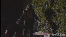 a man with long hair and a beard is standing in front of a bush with the word xangelix on the screen .