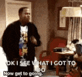 a man is dancing in a living room while a woman sits in a chair .