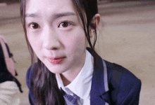 a close up of a girl in a school uniform making a face .