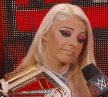 a woman is holding a championship belt and talking into a microphone .