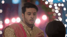 a man with a red bindi on his forehead points at a woman