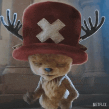 a stuffed animal is wearing a red hat with antlers and a cross on it