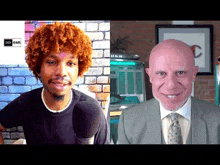 a man with curly hair and a bald man in a suit are talking to each other .