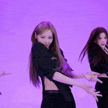 a woman in a black shirt is dancing in front of a purple wall
