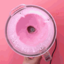 a person is holding a blender with pink liquid inside