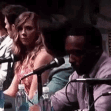 a group of people are sitting in front of microphones .