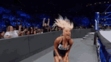 a woman is dancing in a wrestling ring with a crowd watching .
