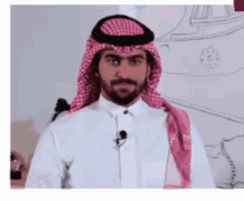 a man with a beard wearing a white shirt and a pink scarf