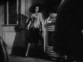 a black and white photo of a woman standing in a doorway