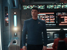 a man in a star trek uniform stands in front of a display that says ' ships warp '