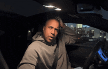 a man is sitting in a car with a sign in the background that says ' jcpenney ' on it