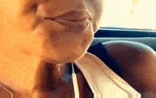 a woman is making a funny face in a car while smoking a cigarette .